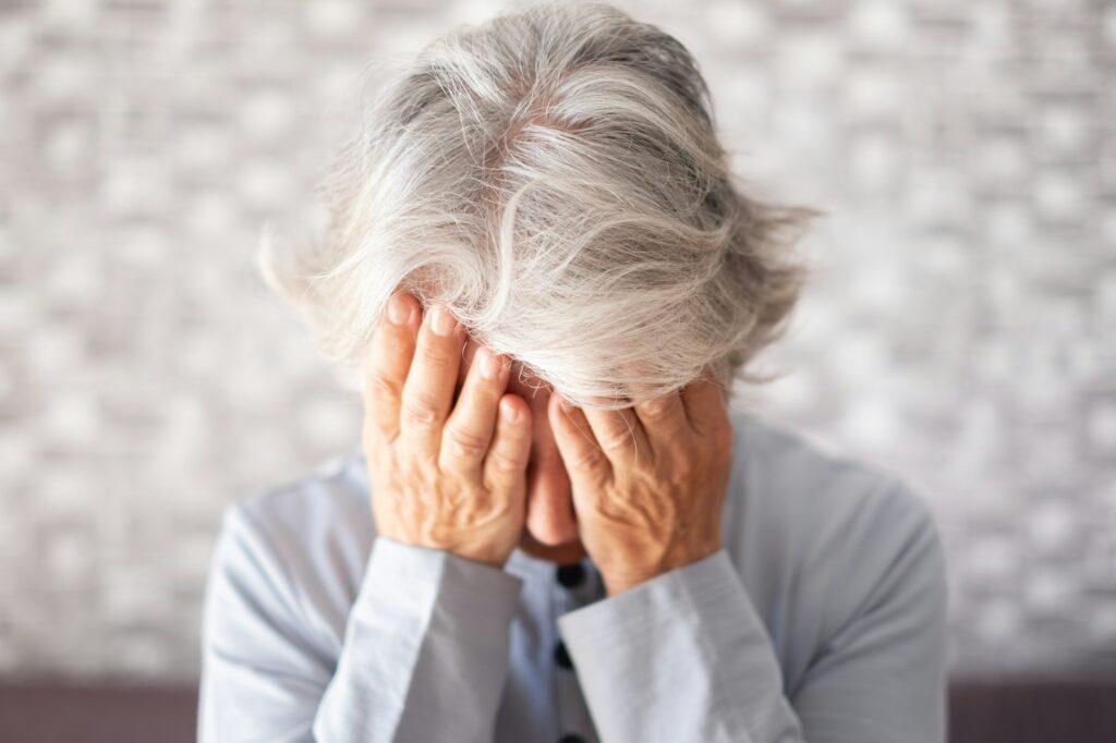 Frustrated unhappy old senior woman with hands on her face, elderly female suffering for divorce