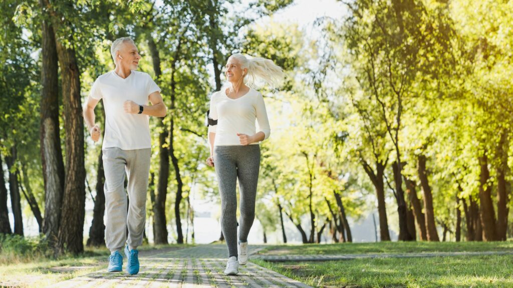 Full length of healthy mature couple jogging in park at early morning