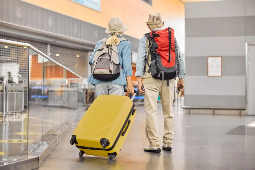 Two Caucasian elderly travelers standing at the airport